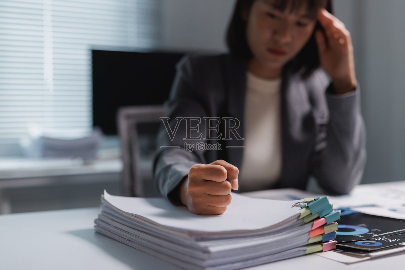 一位女商人在堆积如山的办公室文书工作中感到压力重重照片摄影图片