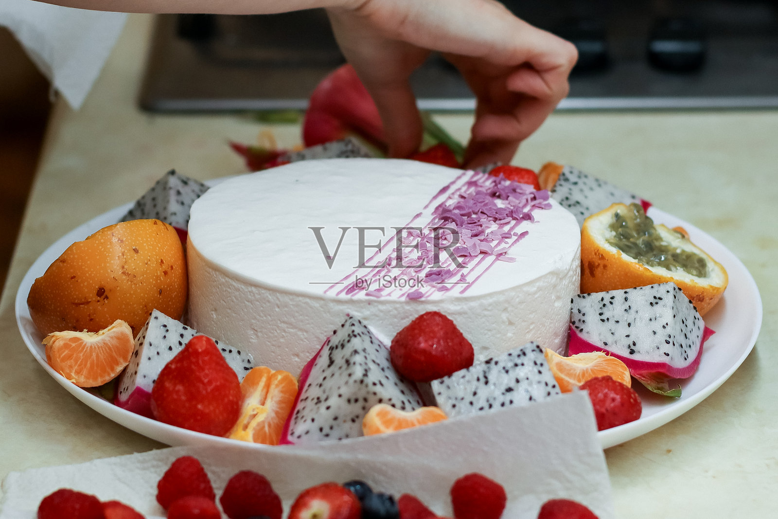手在白色蛋糕上摆放水果和热带装饰照片摄影图片