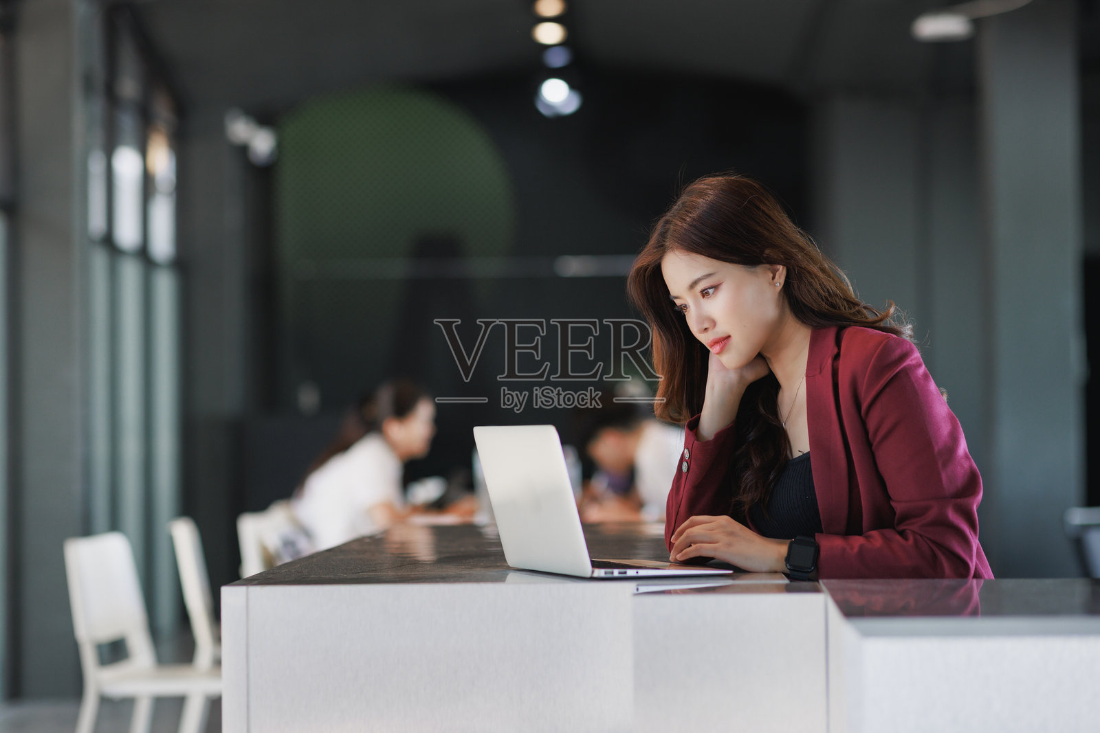 年轻女子在现代办公室里用笔记本电脑工作照片摄影图片