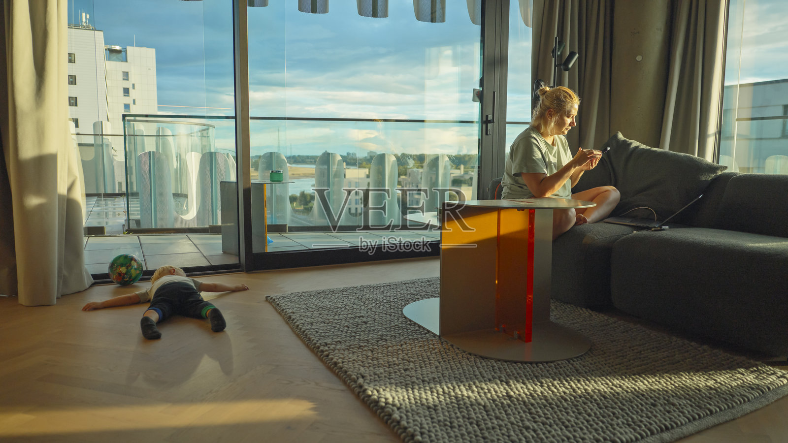 白种女人在家办公，旁边有蹒跚学步的孩子照片摄影图片