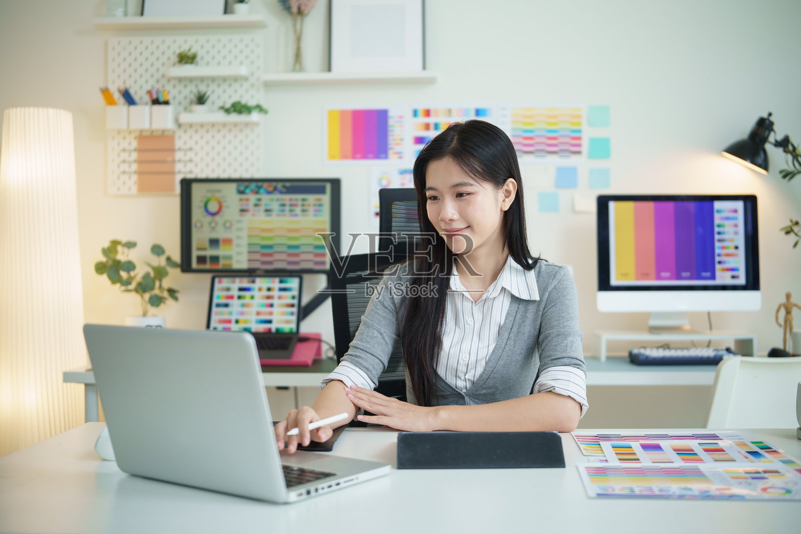 一位年轻的女性平面设计师在现代创意办公室用笔记本电脑工作。照片摄影图片