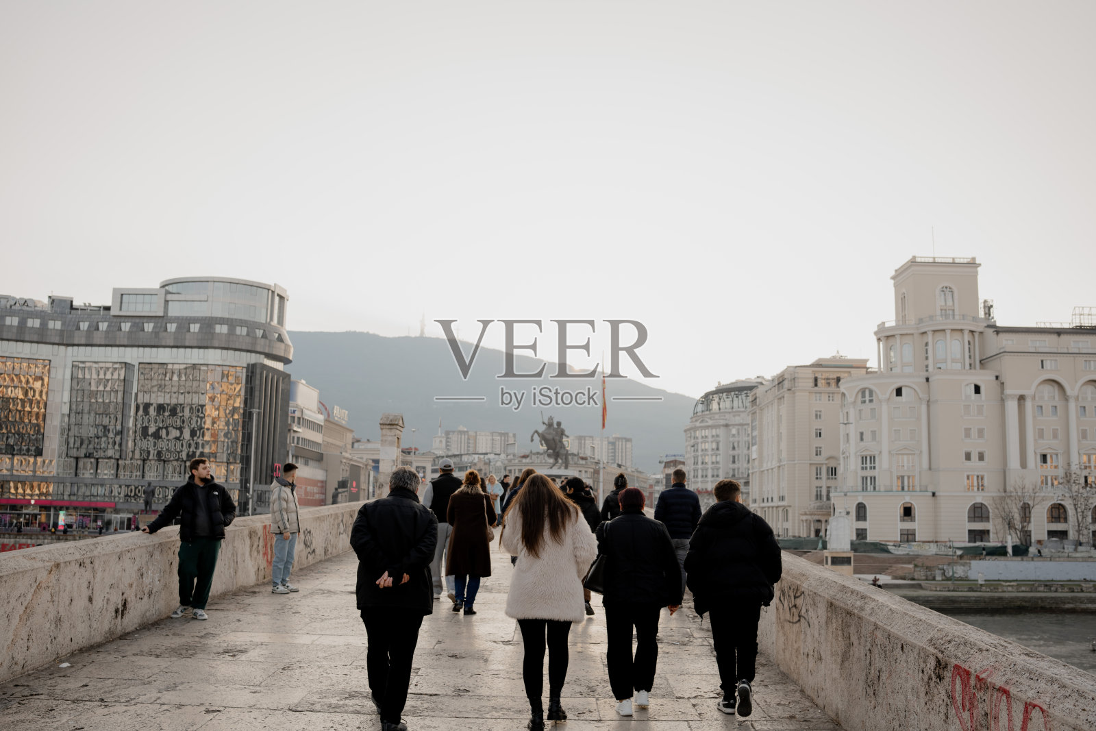 冬日午后，行人在城市桥上行走照片摄影图片