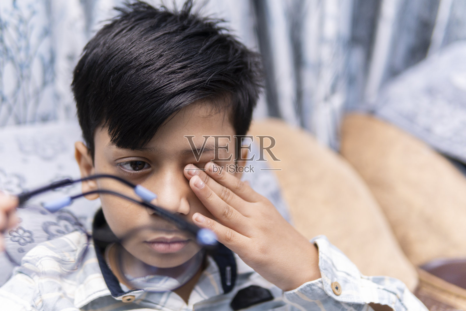 印度小男孩摘下眼镜揉眼睛照片摄影图片