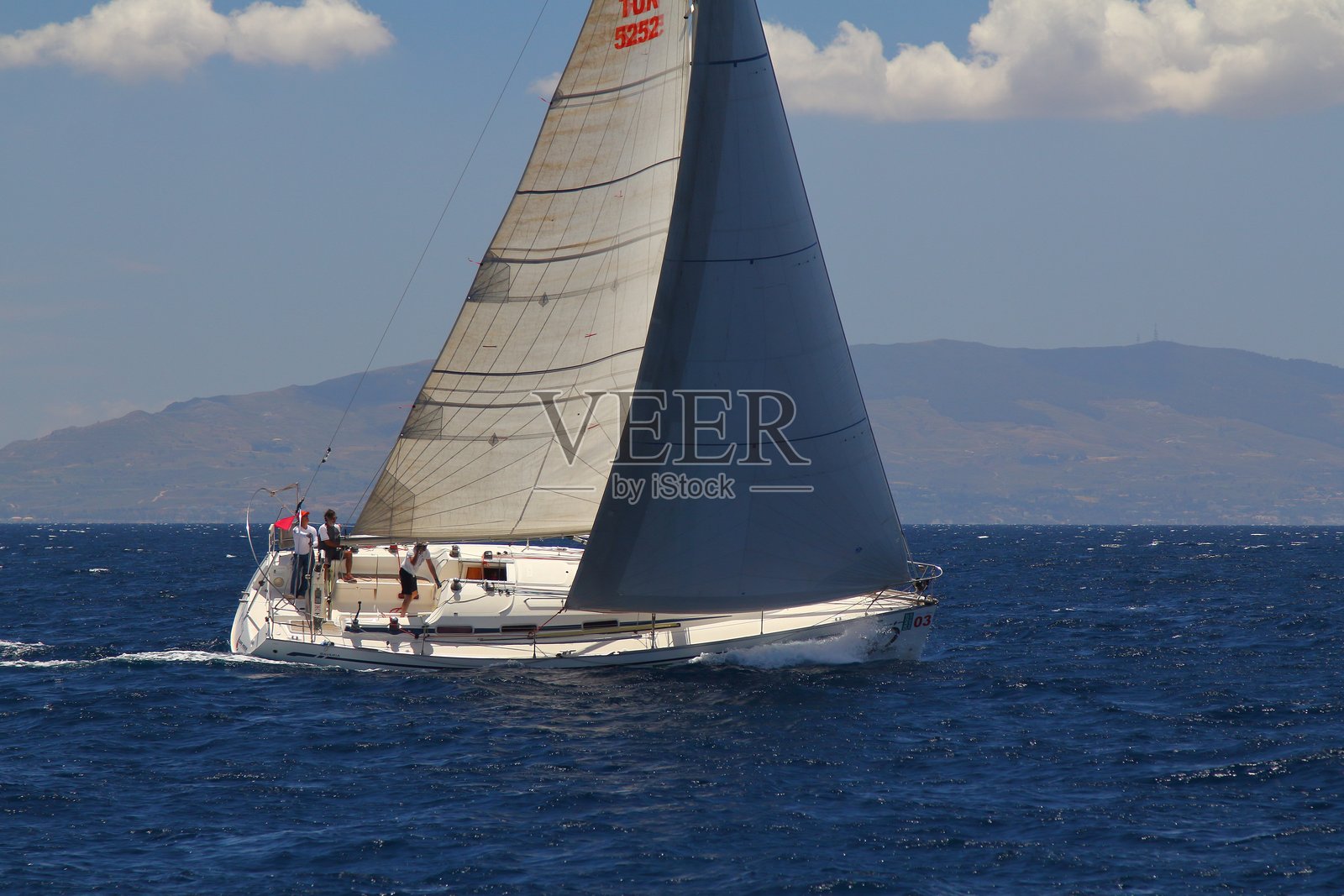 帆船在爱琴海的蓝色水域中乘风破浪，这里是著名的度假胜地博德鲁姆的海岸线。照片摄影图片