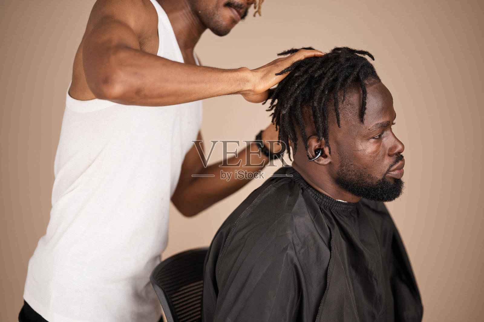 理发师正在为坐着的男顾客打理脏辫照片摄影图片