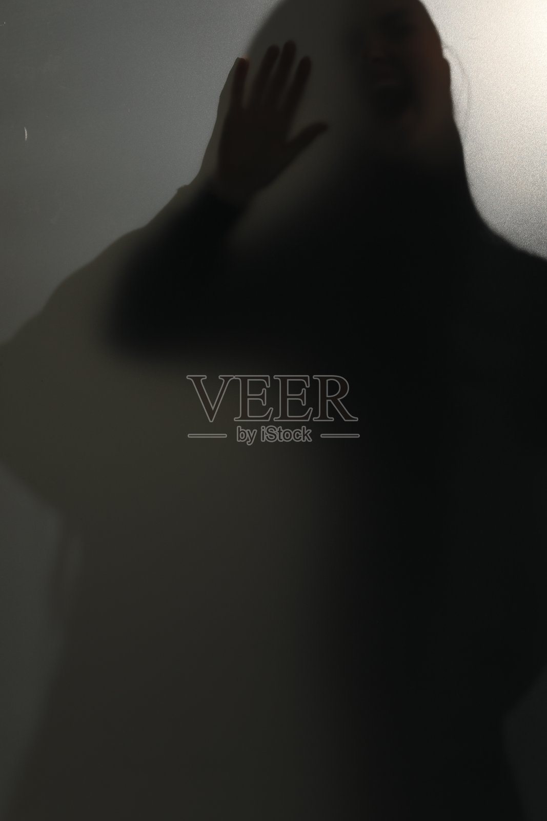 玻璃后面鬼魂的剪影，背景为浅灰色照片摄影图片