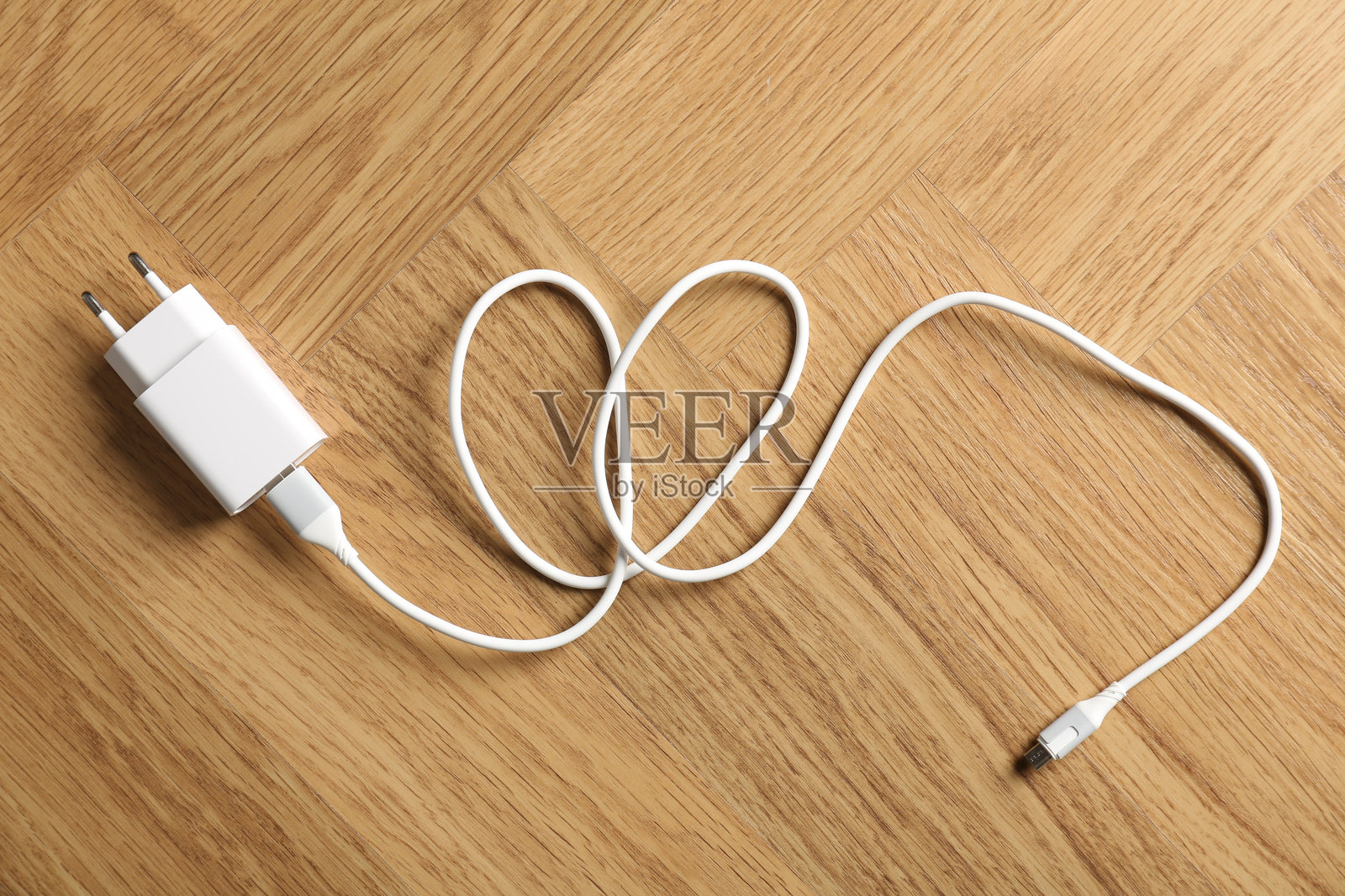 木桌上的USB电源适配器和充电线，俯视角度照片摄影图片
