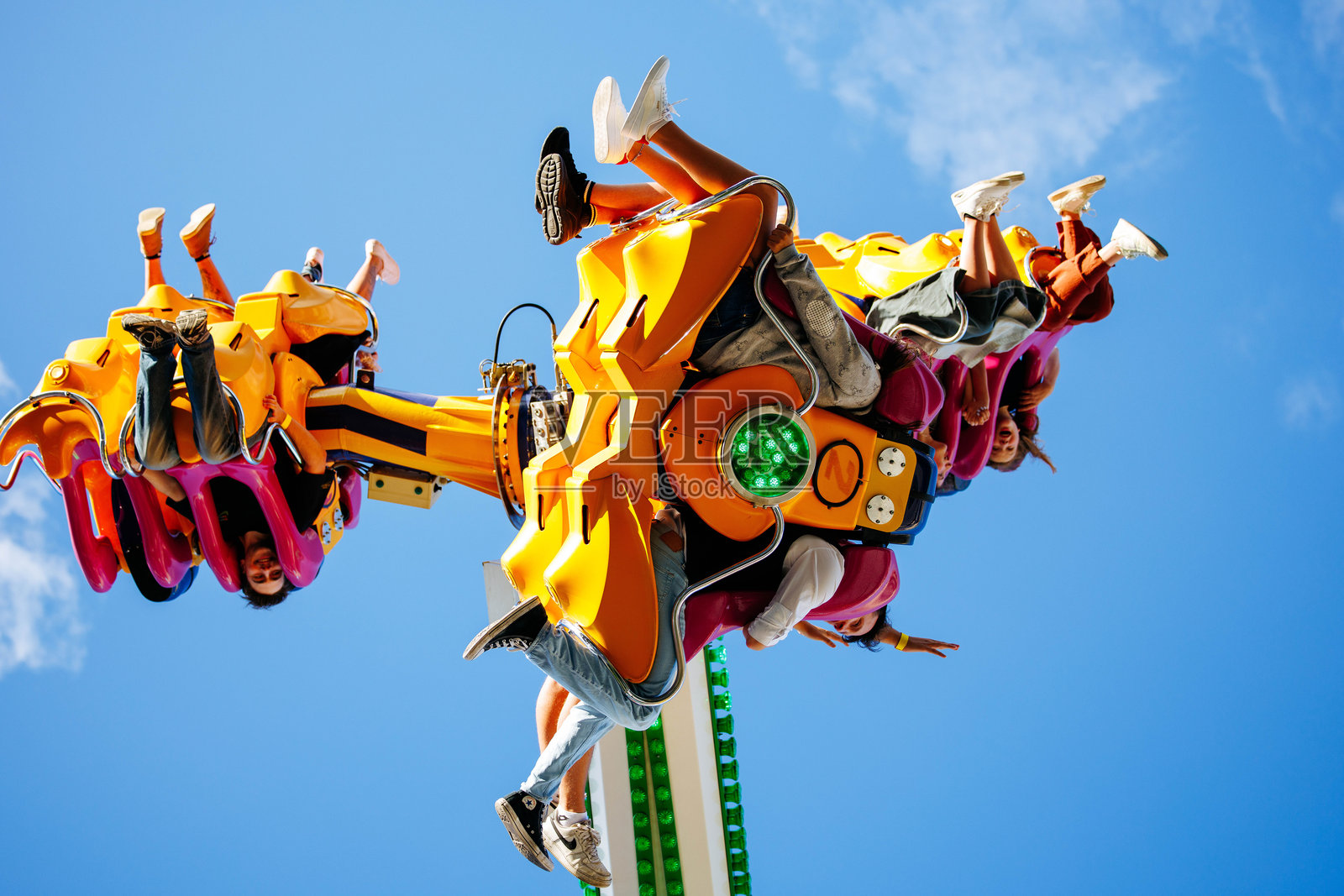 在明媚的蓝天下，惊险刺激的游乐园游乐设施载着兴奋的游客倒置，展现出节日的欢乐氛围照片摄影图片