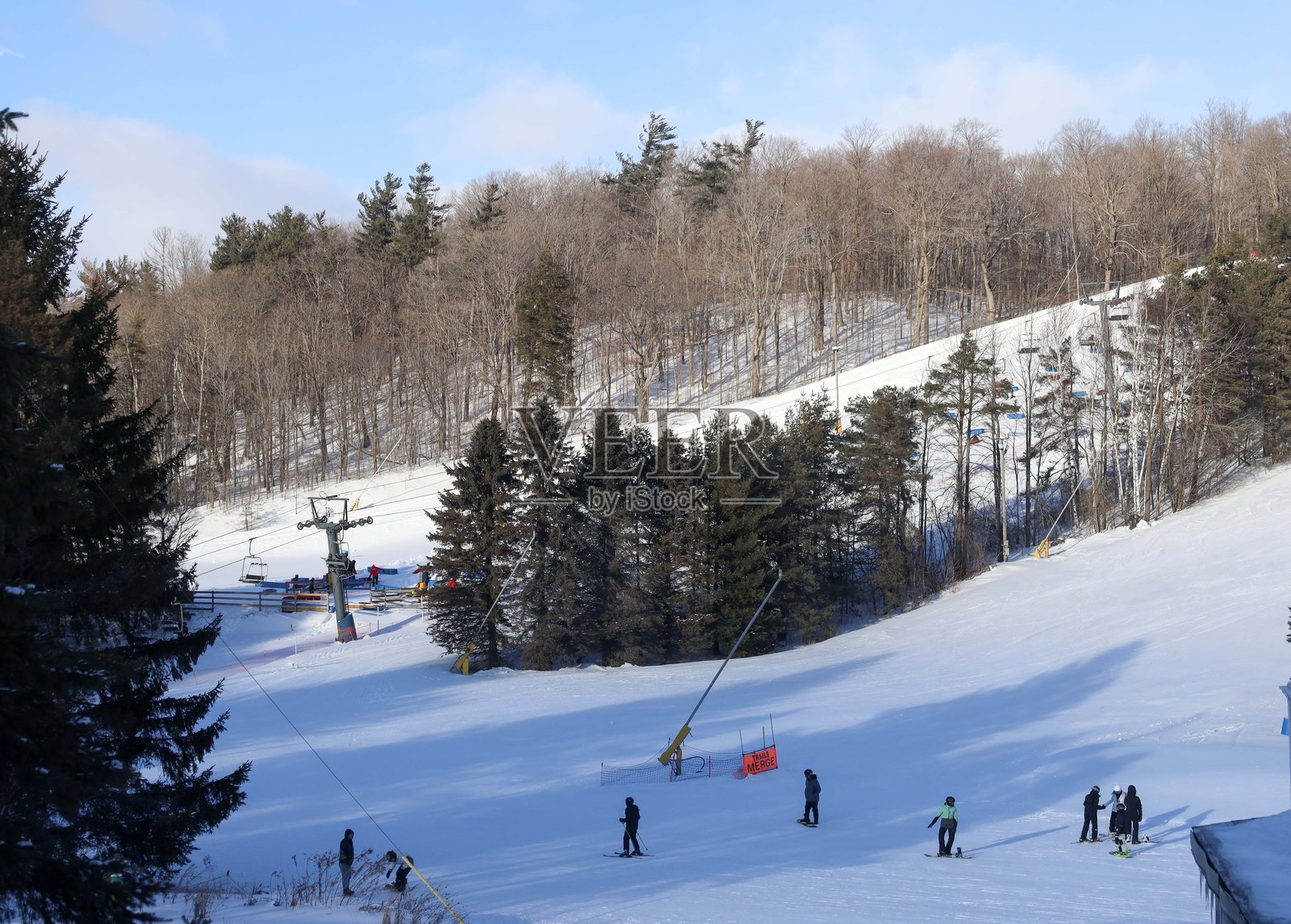 一幅广阔的冬季风景展现在画面中,展示了一个生机勃勃的安大略滑雪胜地,坐落在被雪覆盖的常绿树林之间。照片摄影图片