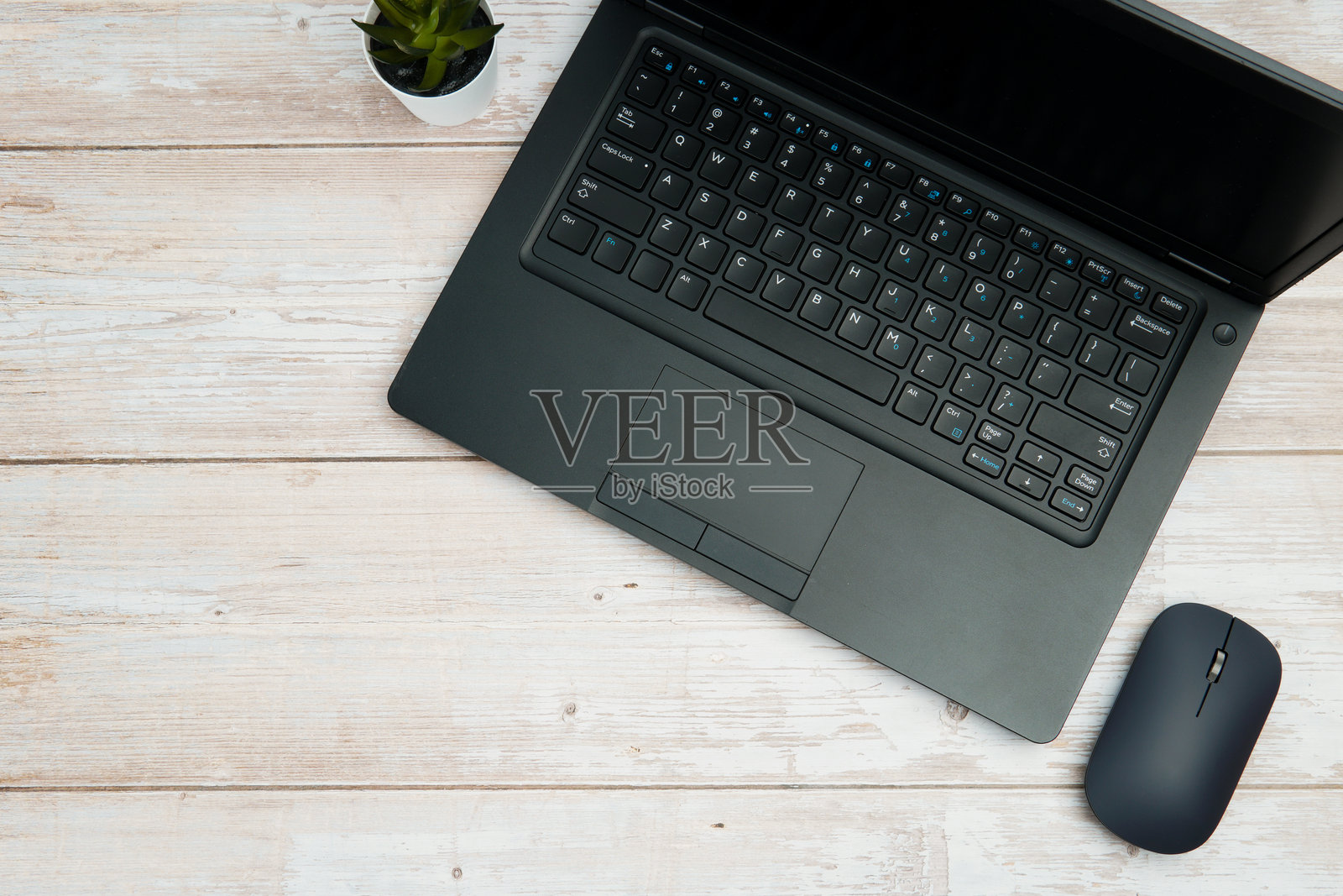 俯视现代商务办公空间，白色木质办公桌上摆放着笔记本电脑、鼠标和绿植，展现了高效、数字化的工作环境和专业的办公室布置，并留有干净的复制空间。照片摄影图片