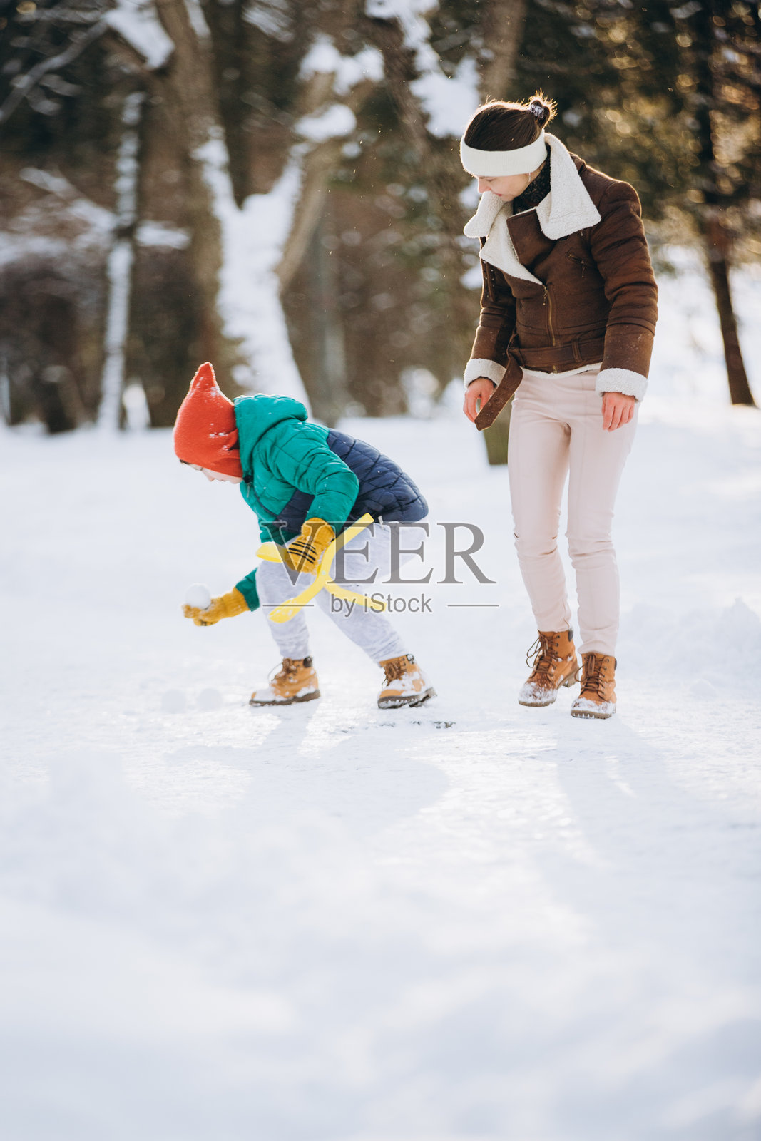 冬天，母亲和儿子在雪中玩耍照片摄影图片