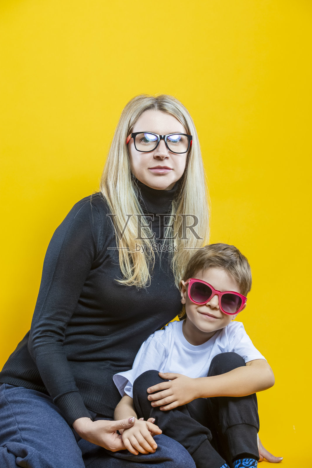年轻快乐的父母夫妇，妈妈和儿子，穿着休闲服，拥抱孩子，直视前方，孤立在黄色背景上，作为母亲节的概念照片摄影图片