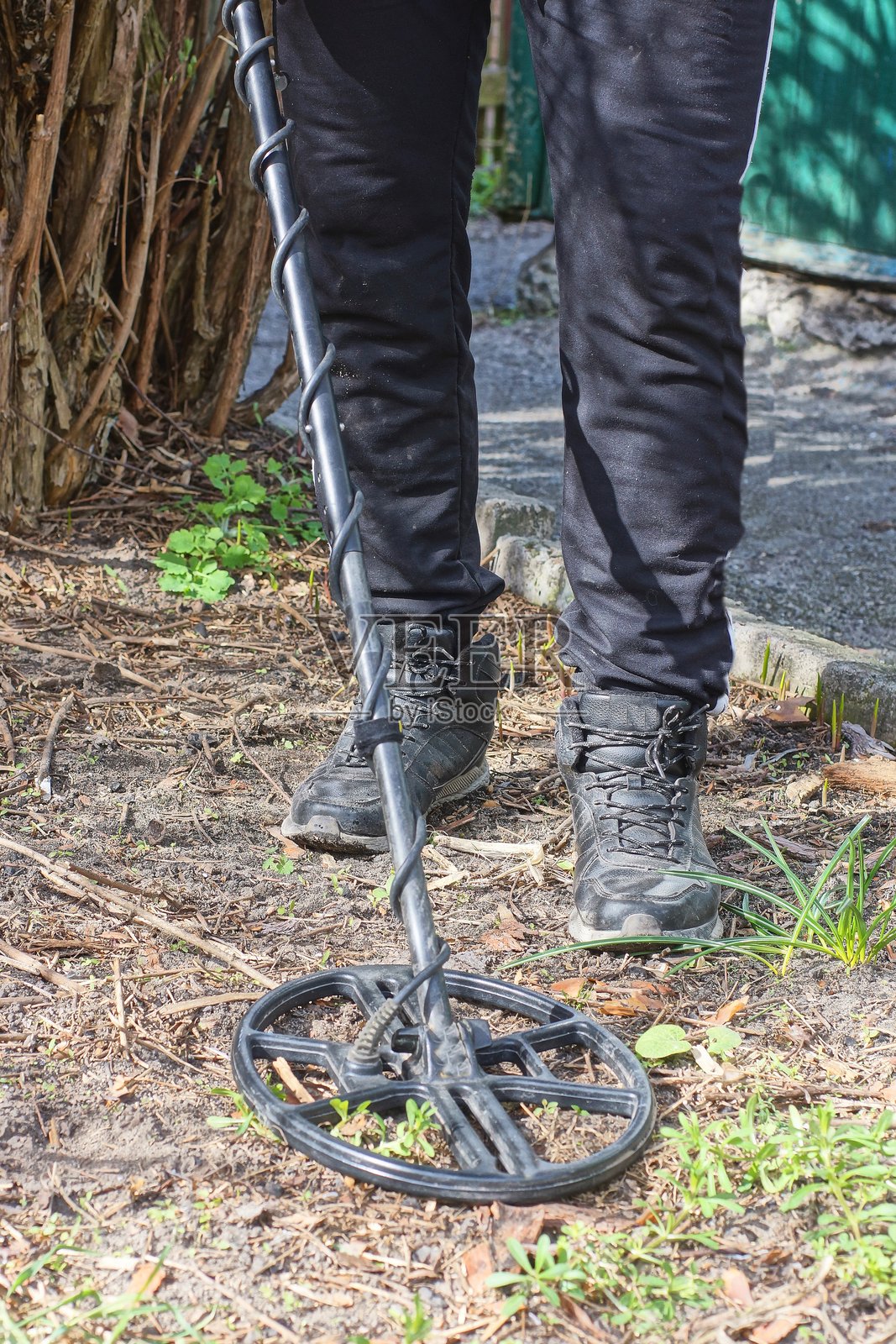一名身穿黑色衣服、头戴帽子的男子手持金属探测器照片摄影图片