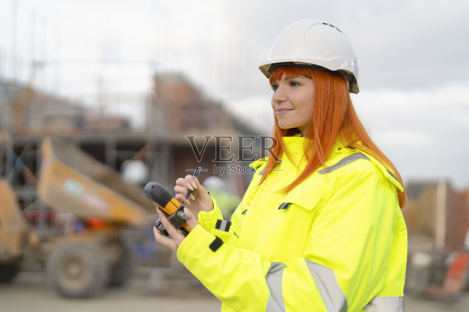 建筑工地上，一位身穿亮黄色安全服的女施工经理正在使用坚固的平板电脑照片摄影图片