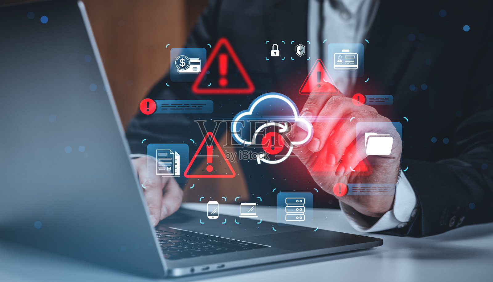 商人在黑暗的办公室背景下，在笔记本电脑上方的未来派界面上与全息云安全警报图标互动，概念是数据风险。照片摄影图片