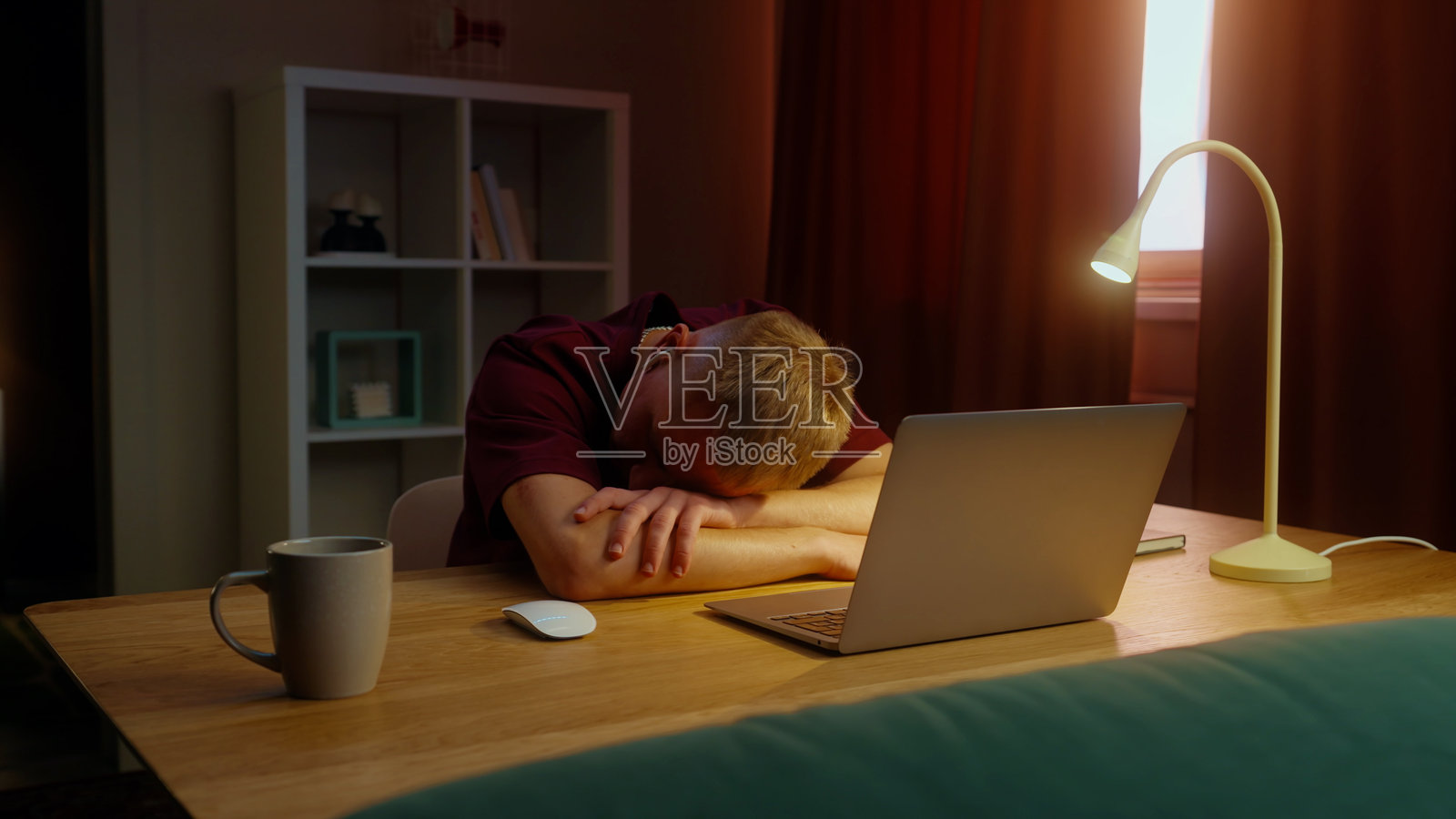 疲惫的男人在办公桌旁的笔记本电脑旁睡着了。疲倦、困倦、懒惰的人。照片摄影图片