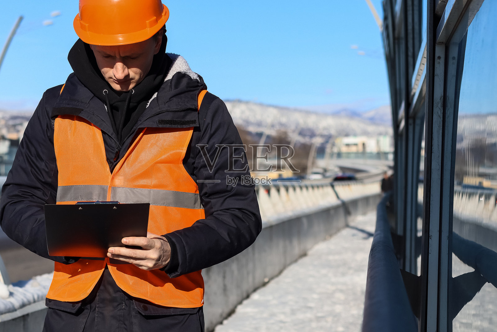 戴头盔的穿马甲的工人在雪景中查看剪贴板照片摄影图片