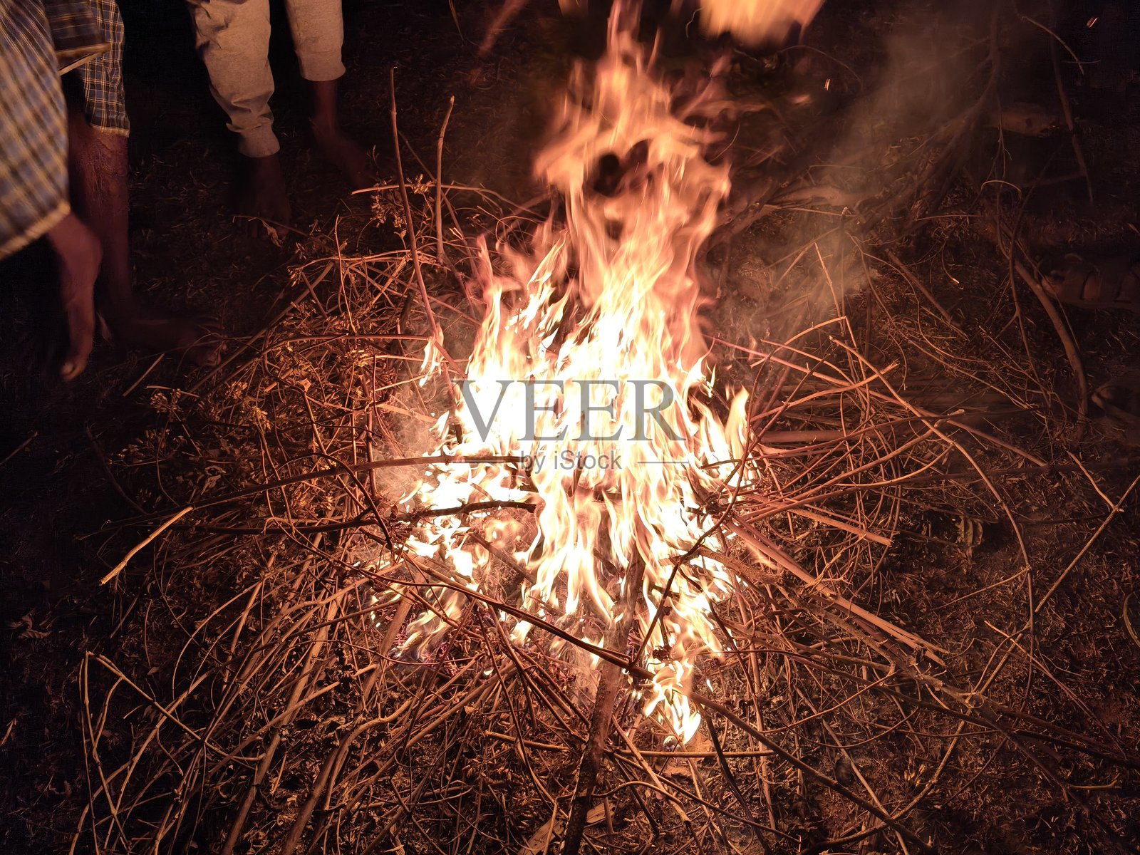 人们在篝火旁烘烤双手和双脚照片摄影图片