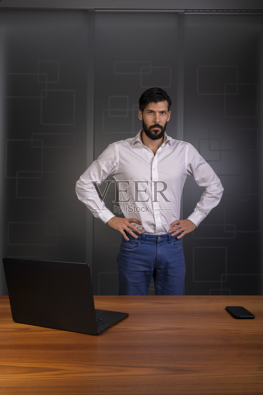 身穿白衬衫和蓝色裤子的男士站在现代办公室，代表企业或公司照片摄影图片