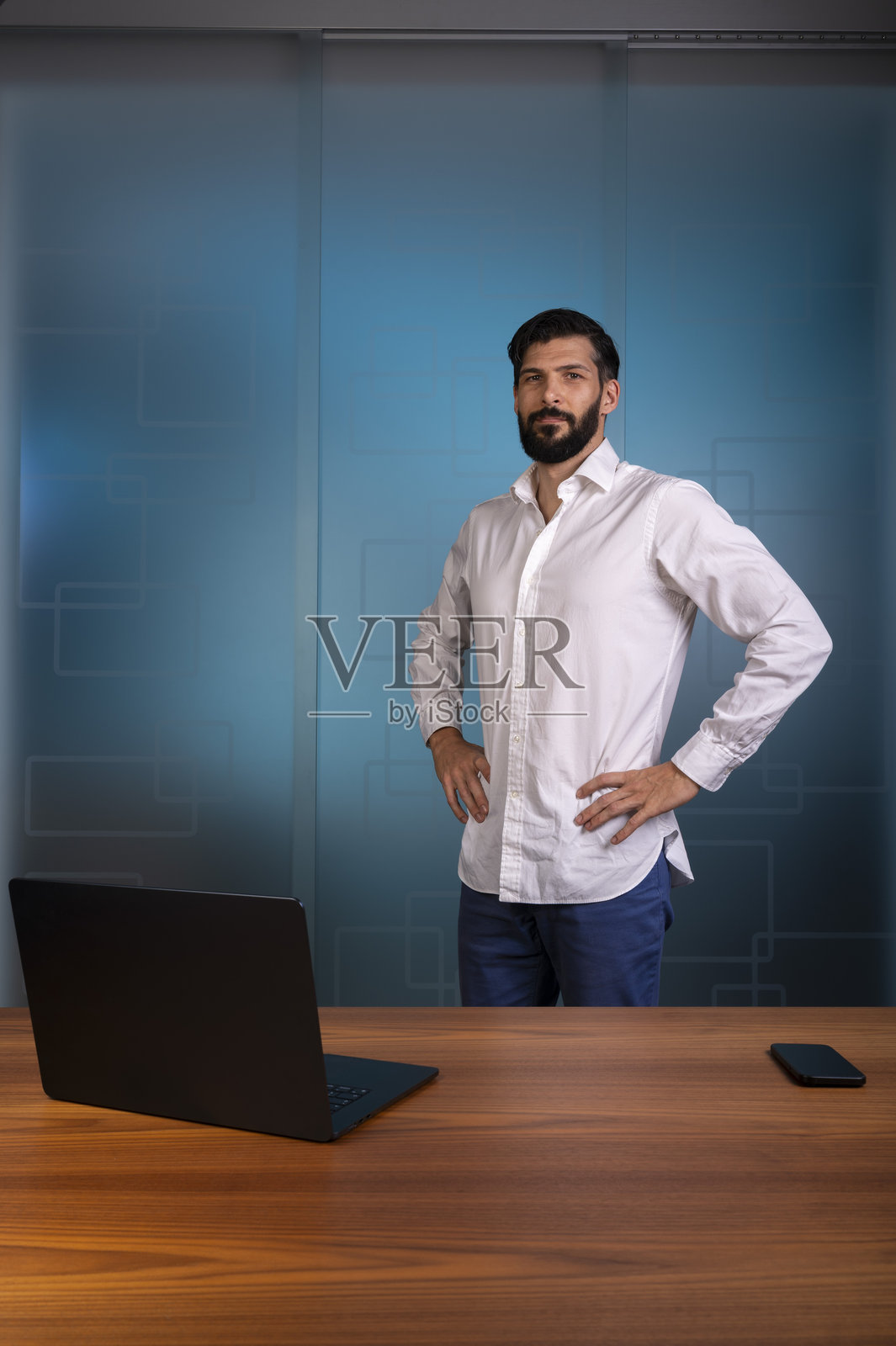 身穿白衬衫和蓝色裤子的男士，站在现代办公室，代表企业或公司照片摄影图片