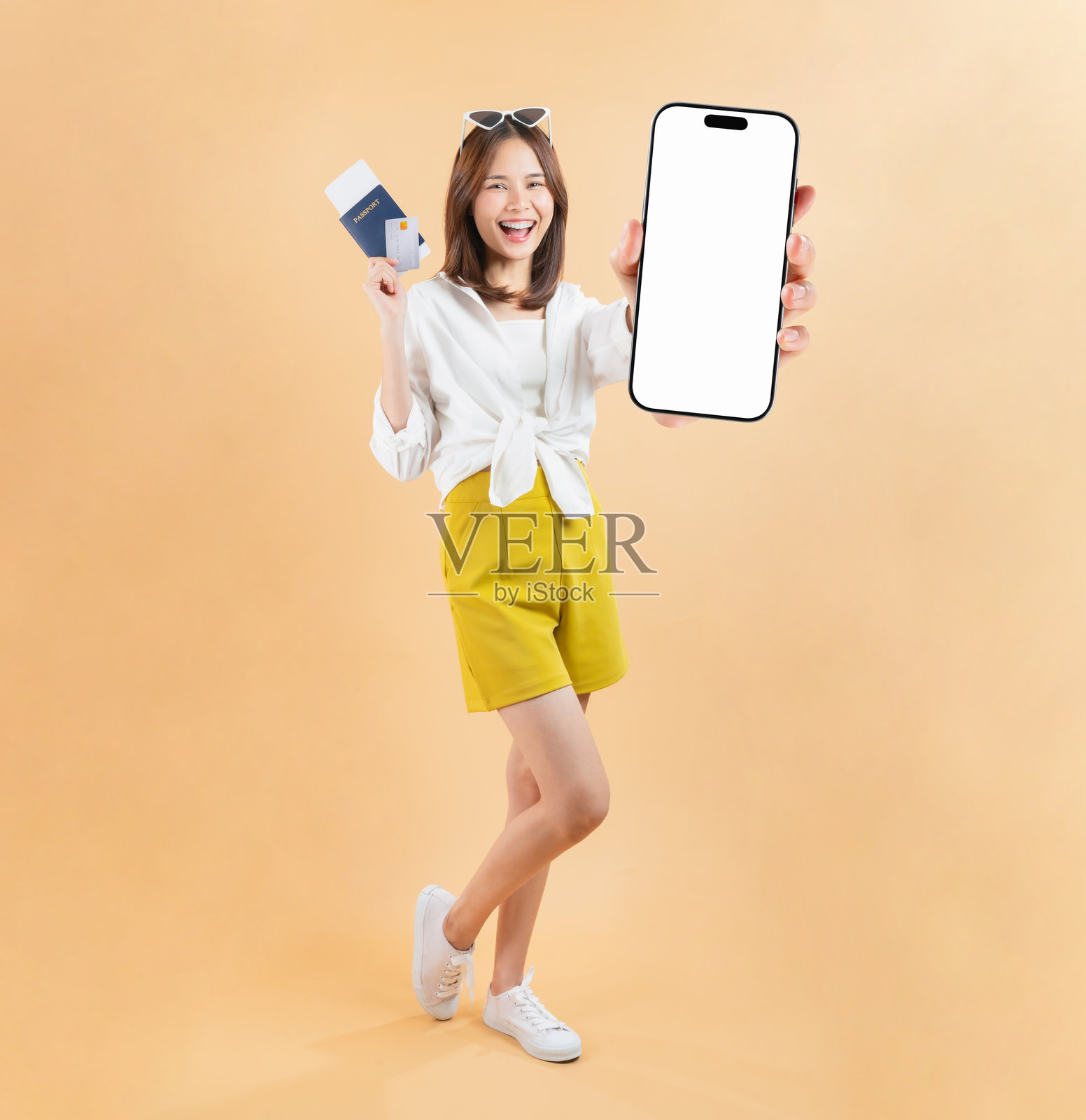 充满活力的亚洲女性准备度假，手持护照、信用卡和智能手机，背景为柔和的色彩。照片摄影图片