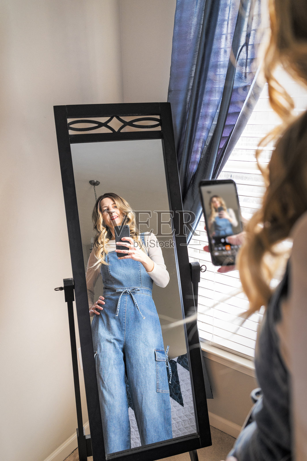 穿着牛仔连体裤的年长女性正在对着镜子自拍照片摄影图片