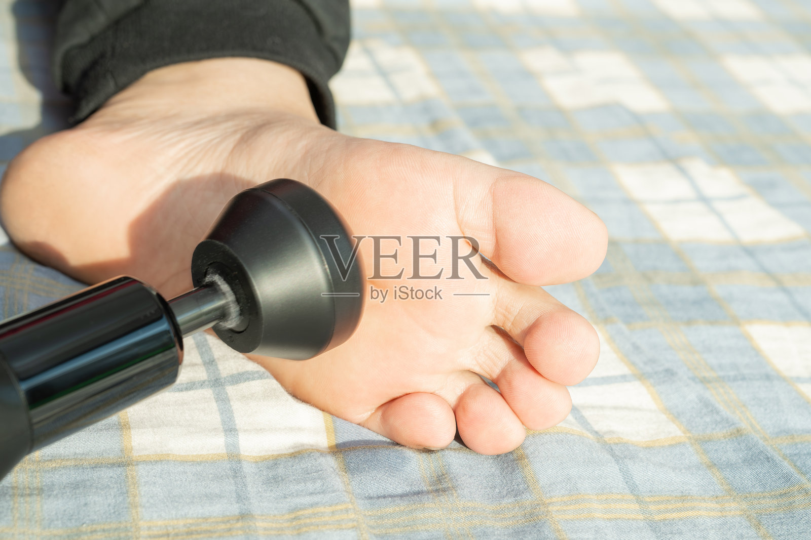 按摩枪快速敲打脚底照片摄影图片