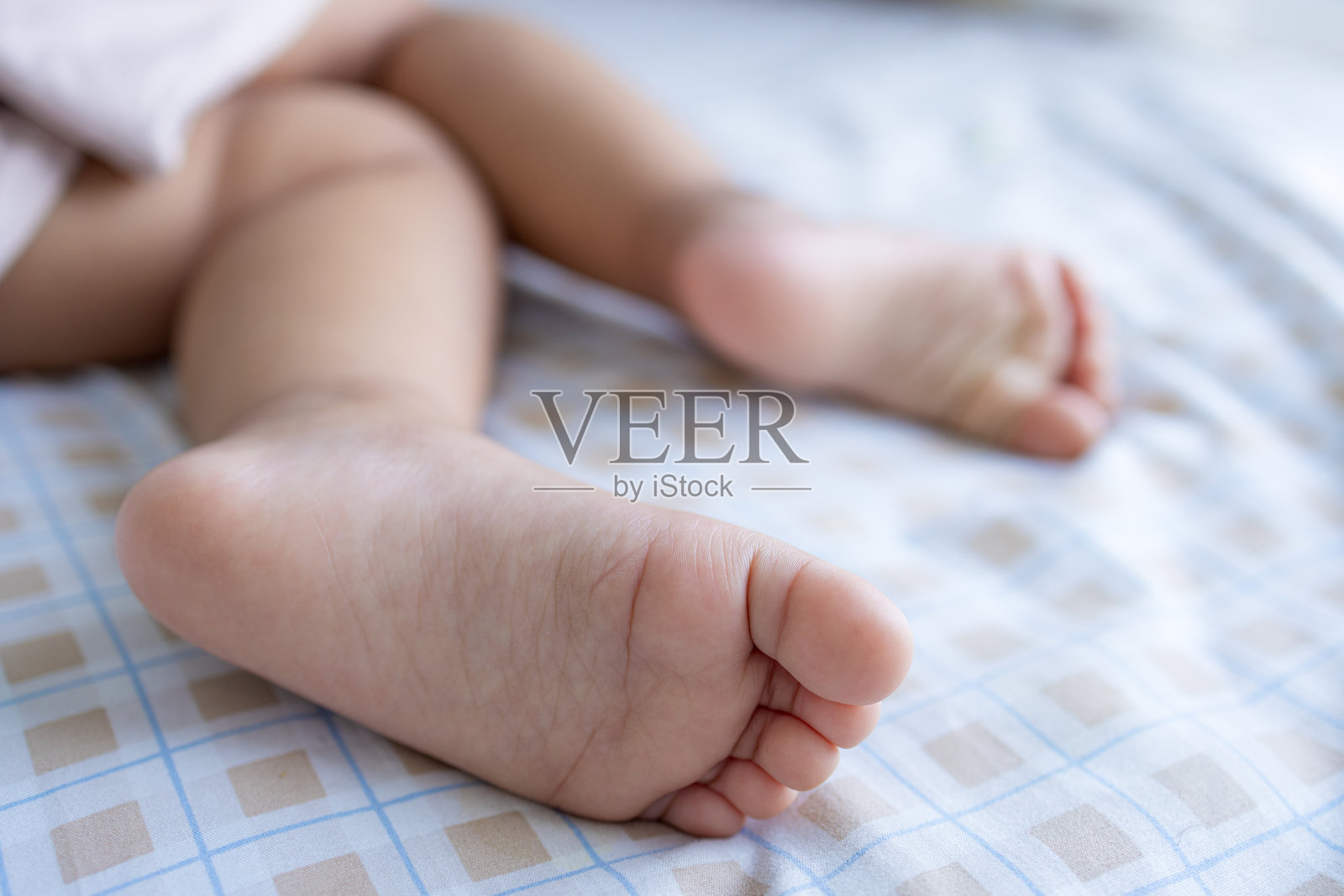 柔软白床上可爱婴儿的小脚特写照片摄影图片