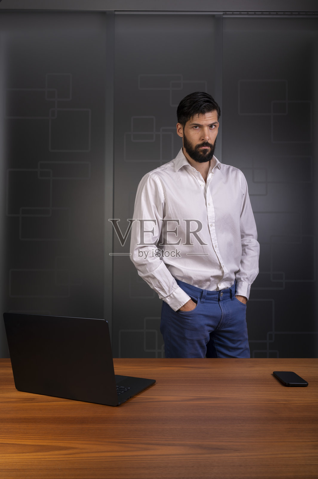 身穿白衬衫和蓝色长裤的男士站在现代办公室，代表企业或公司照片摄影图片