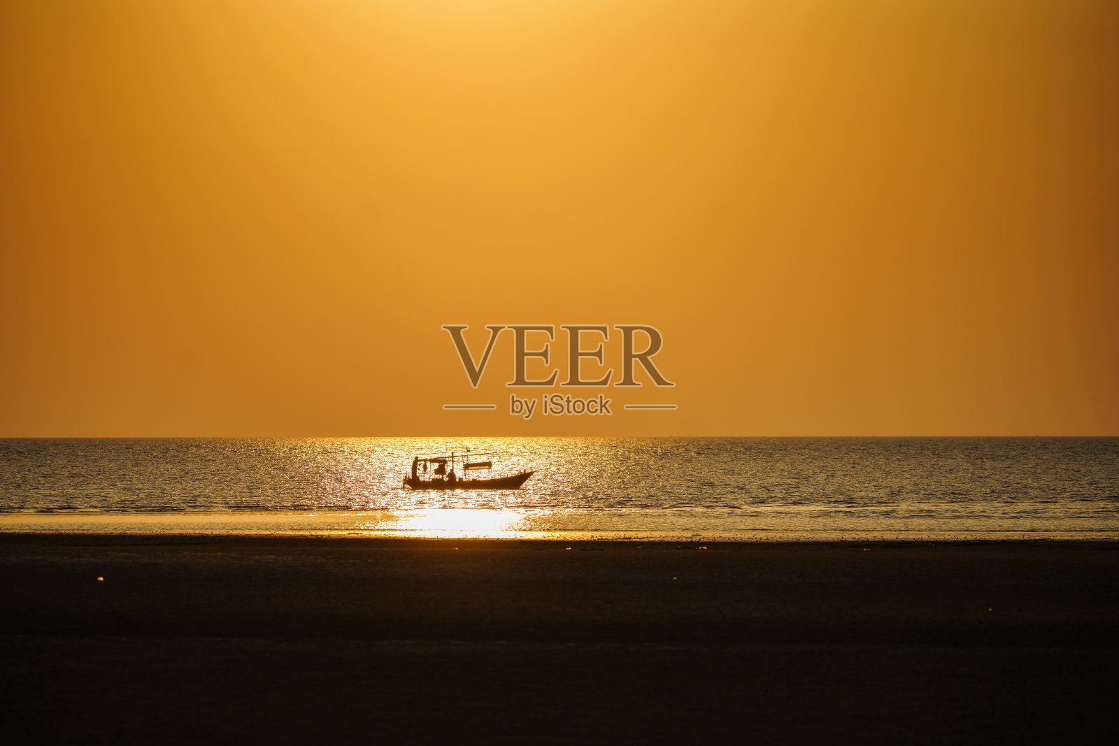 夕阳开始落下，一艘渔船的剪影。照片摄影图片