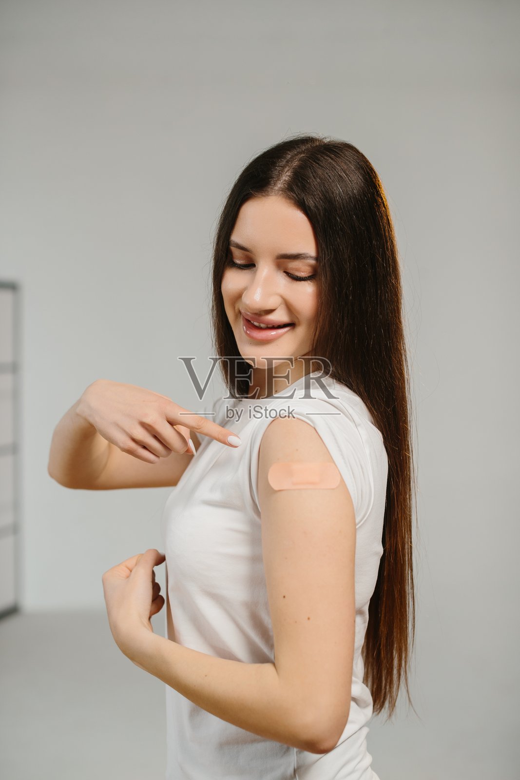 微笑的女性在接种疫苗后展示手臂上的创可贴照片摄影图片