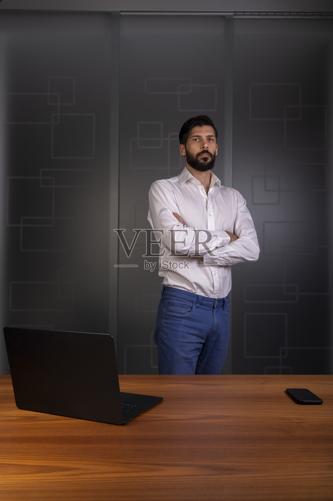 身穿白衬衫和蓝色长裤的男士站在现代办公室，代表公司业务照片摄影图片