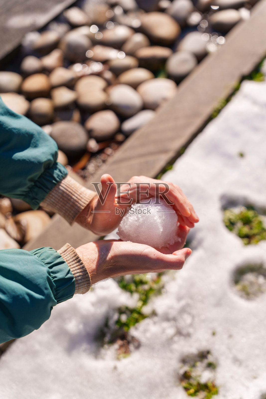 在小雪纷飞的冬天，一个人正在草地上塑形雪。照片摄影图片