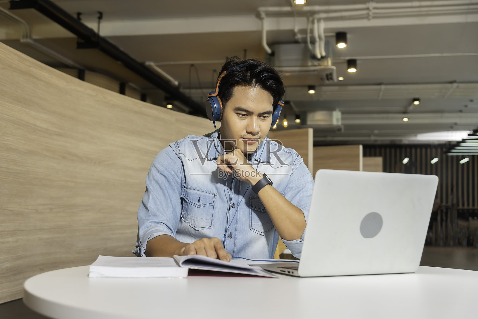 快乐的亚洲呼叫中心代理，戴着耳机，在客户支持办公室与客户交谈。照片摄影图片