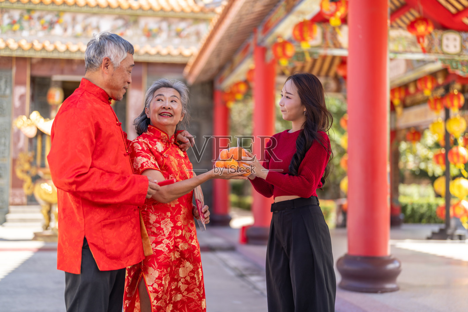 快乐的亚洲女儿在中国寺庙给年长的父母送橘子，一家人庆祝农历新年，孝道、尊敬、幸运和传统节日概念照片摄影图片