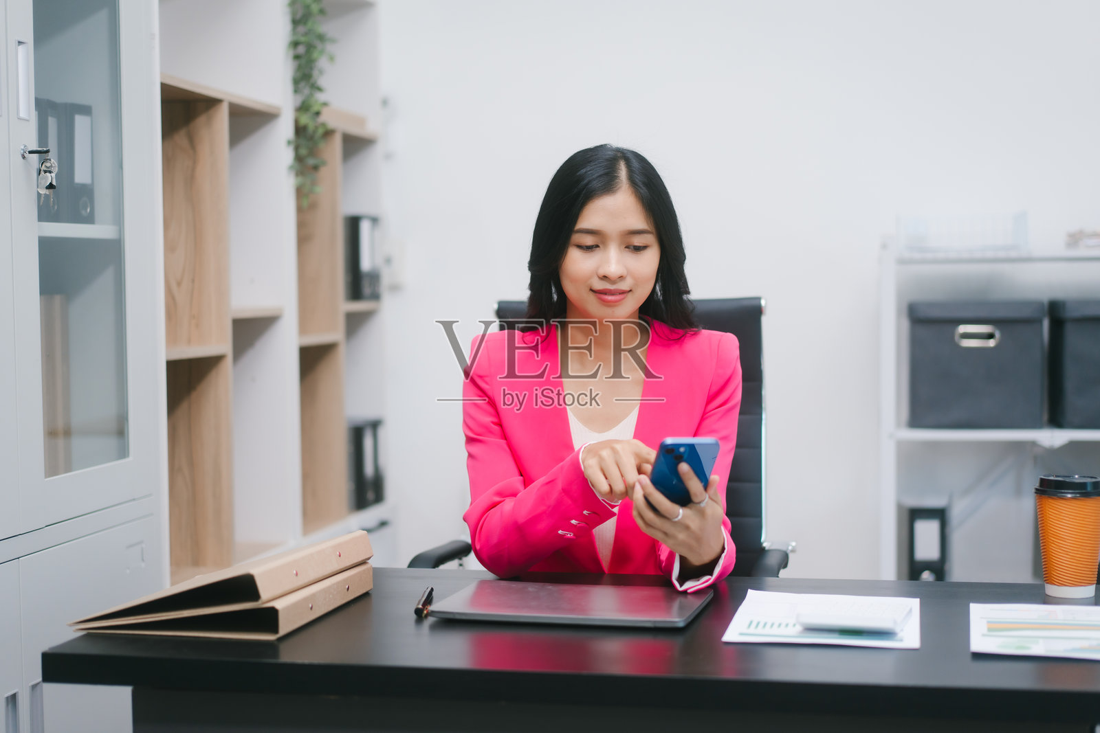 一位自信的亚洲女商人在现代办公室工作，她代表着专业、领导力、成功，并参与公司会议、战略规划和沟通等企业活动。照片摄影图片