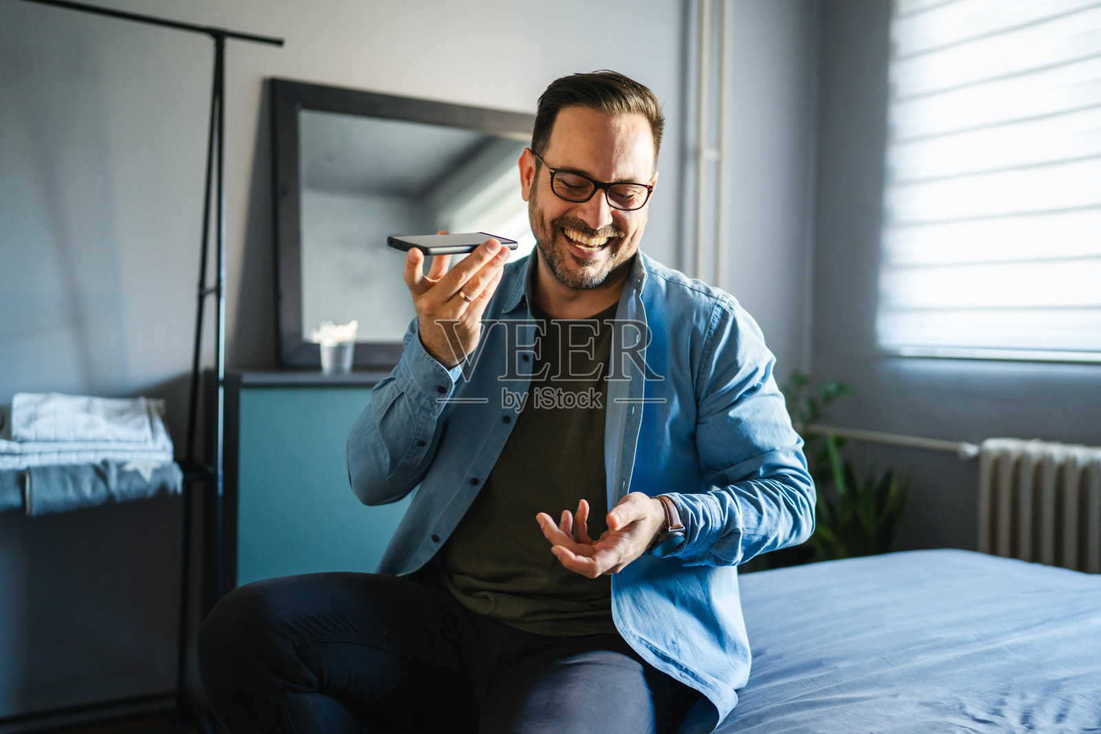 男人在家对着智能手机大笑，发送语音消息照片摄影图片