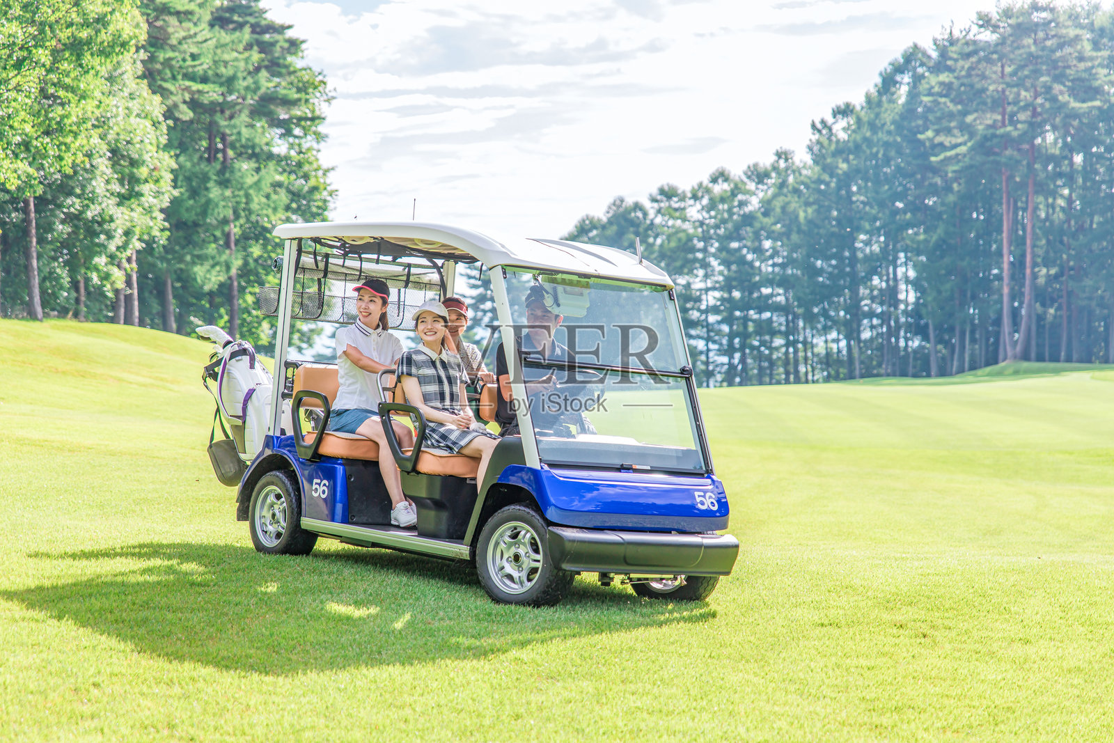 高尔夫球场上，男女高尔夫球手正乘坐高尔夫球车照片摄影图片