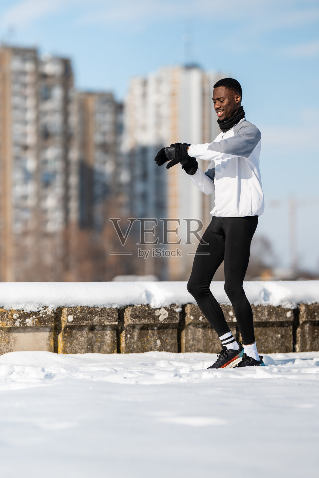 年轻男子在雪中慢跑，查看智能手表数据照片摄影图片