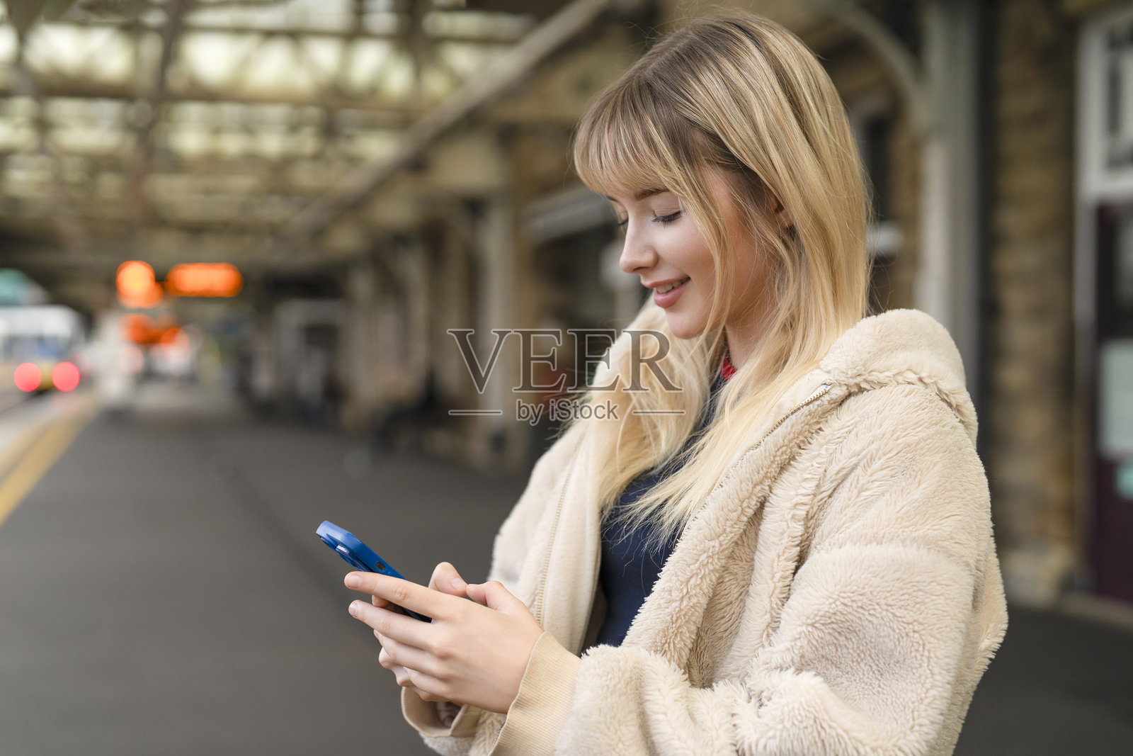 年轻女子白天在火车站候车时使用智能手机照片摄影图片