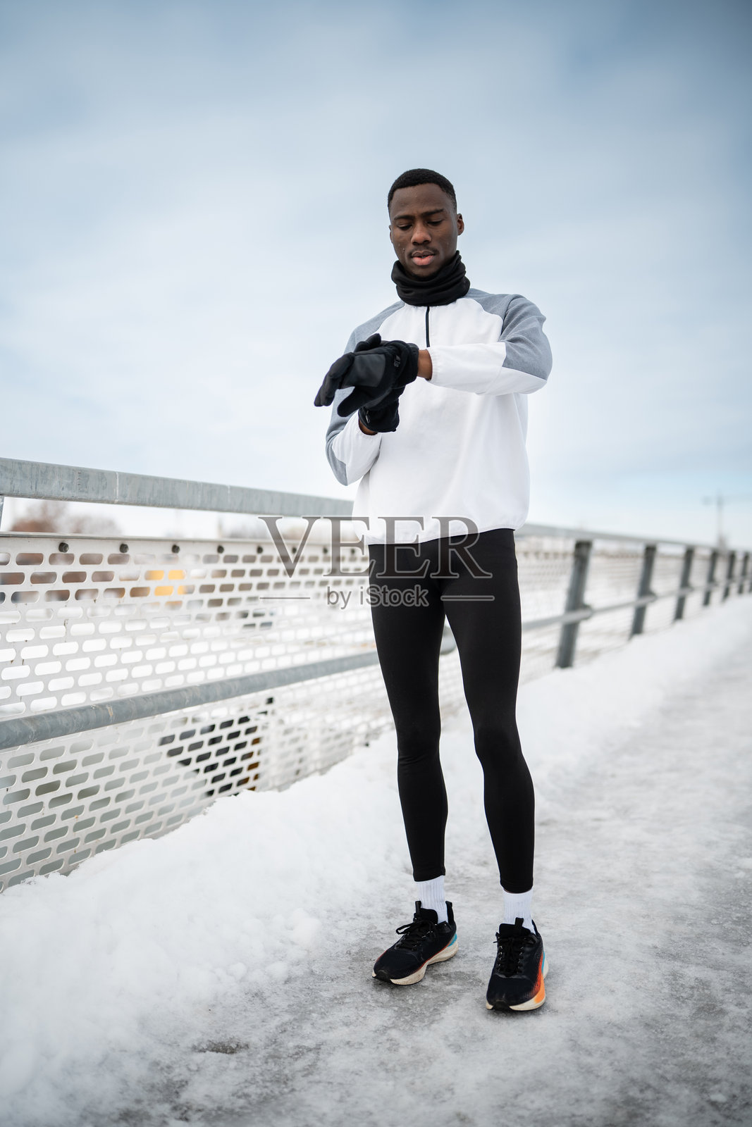 一名黑人男性在冬天跑步时查看智能手表照片摄影图片