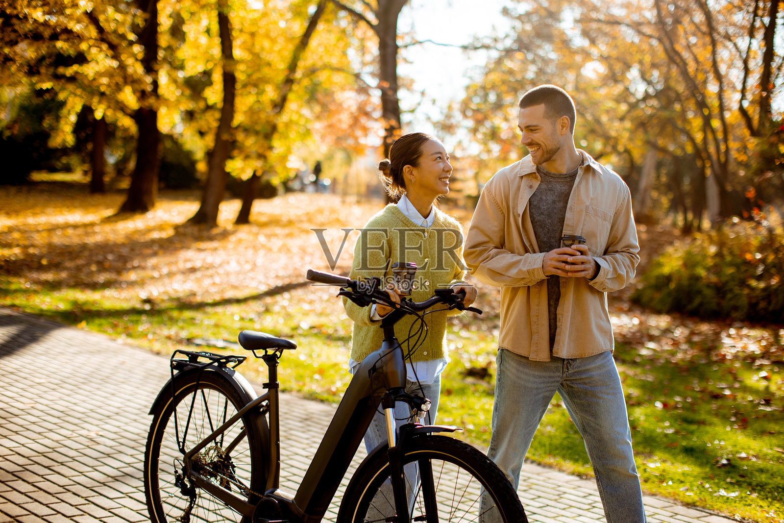 一对情侣在秋日阳光明媚的日子里，骑着自行车一同探索大自然照片摄影图片