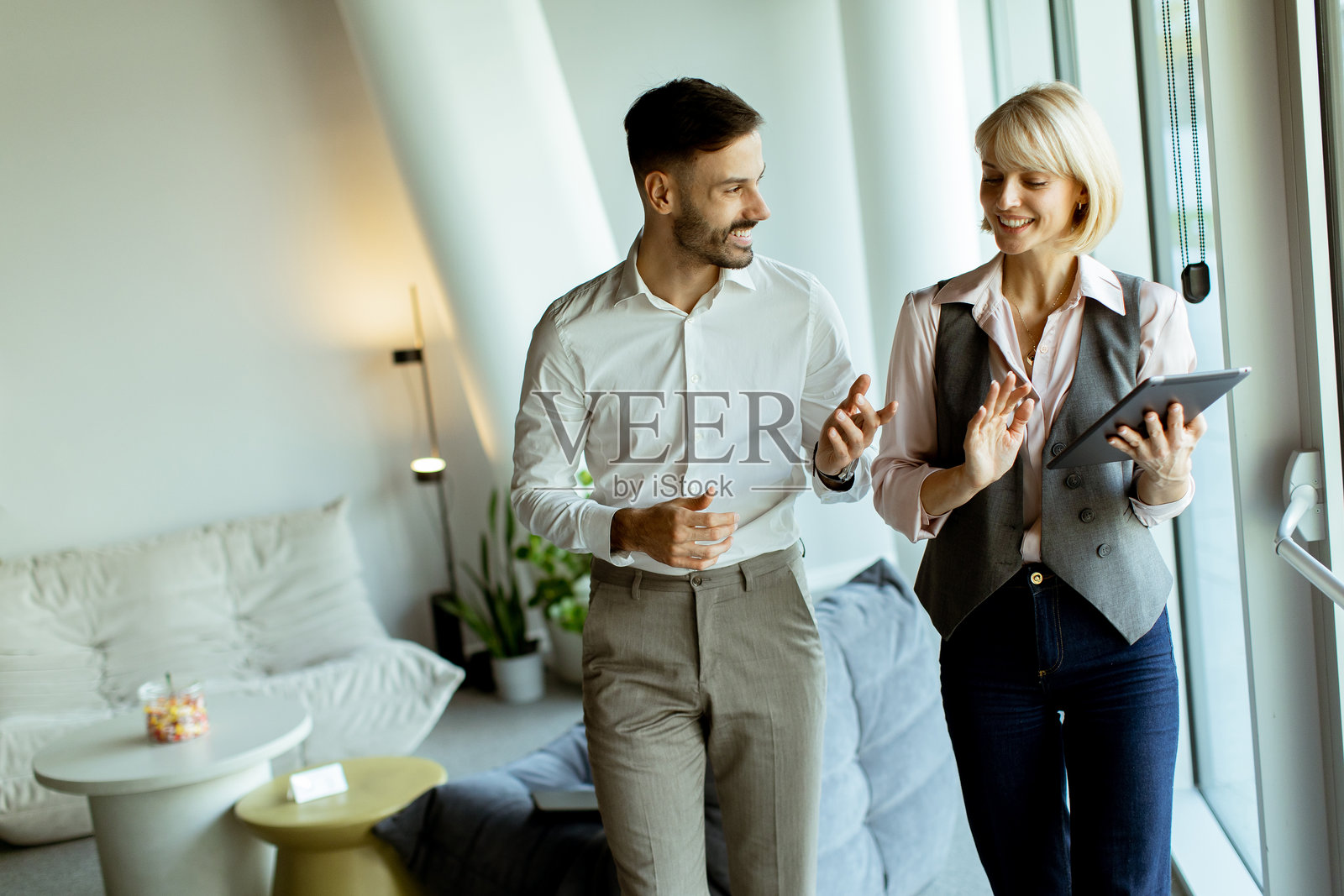 同事们在现代办公室环境中边走边讨论项目创意照片摄影图片