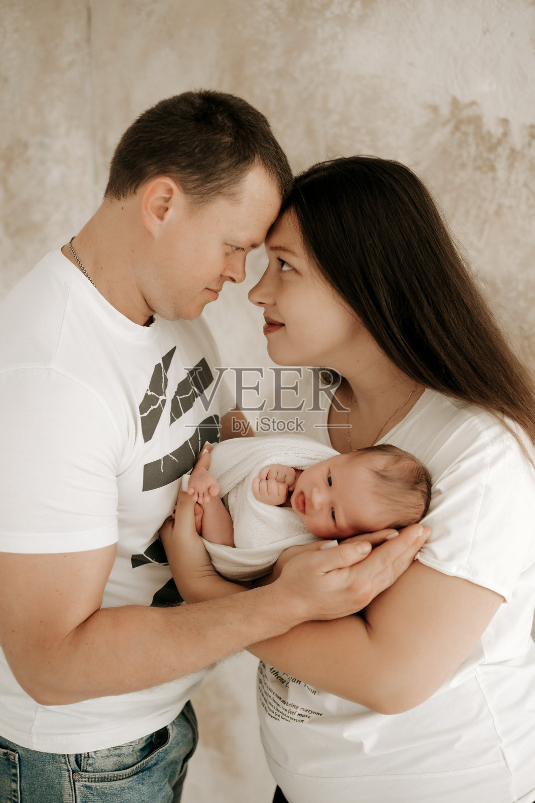 年轻父母抱着新生儿，新手爸妈怀抱中抱着新生儿，一个年轻的家庭照片摄影图片