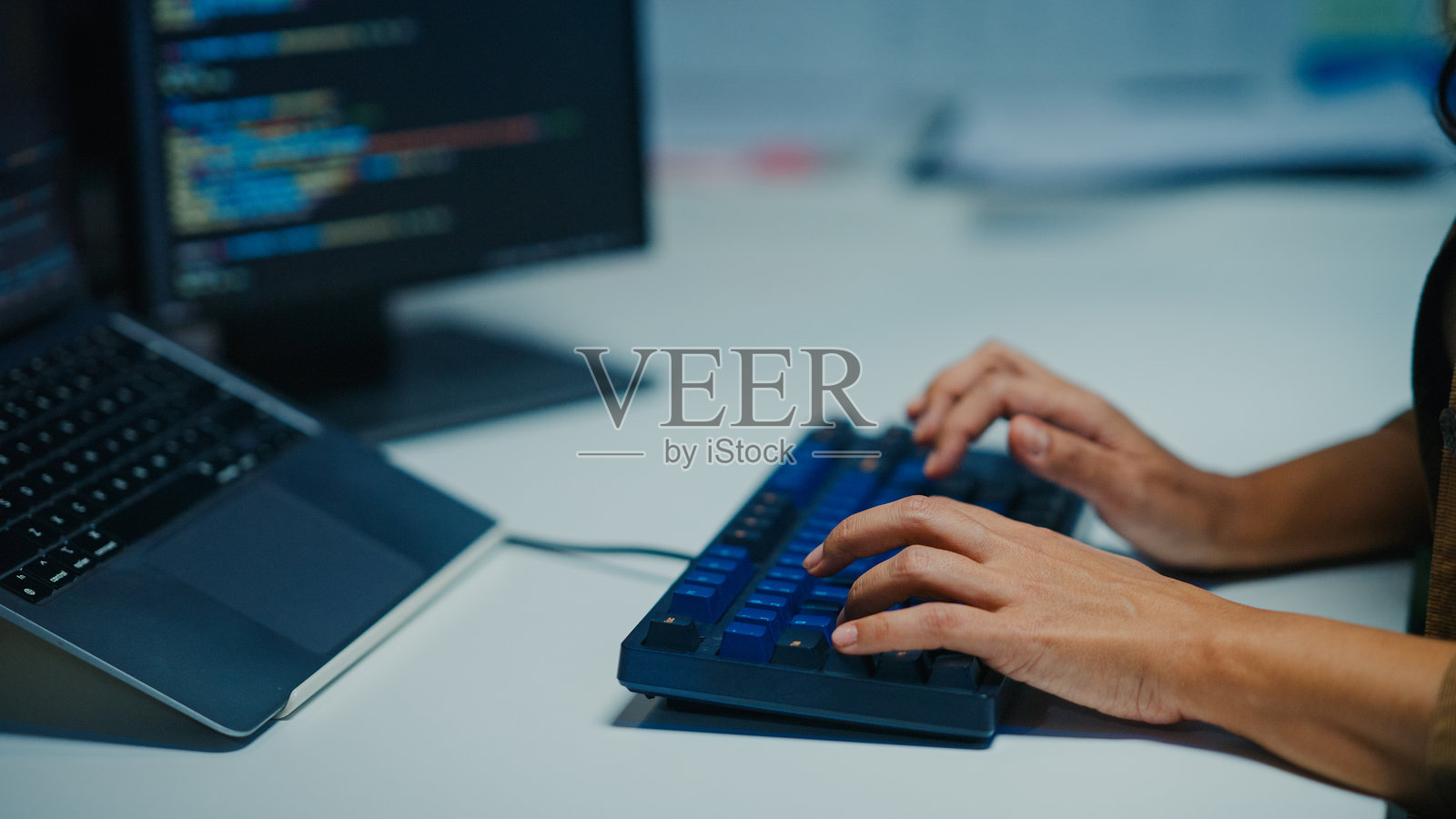 近距离拍摄拉丁裔软件开发人员在夜晚黑暗的办公室里用电脑工作，专注于编写代码和解决复杂的技术问题，涉及人工智能和编程。照片摄影图片