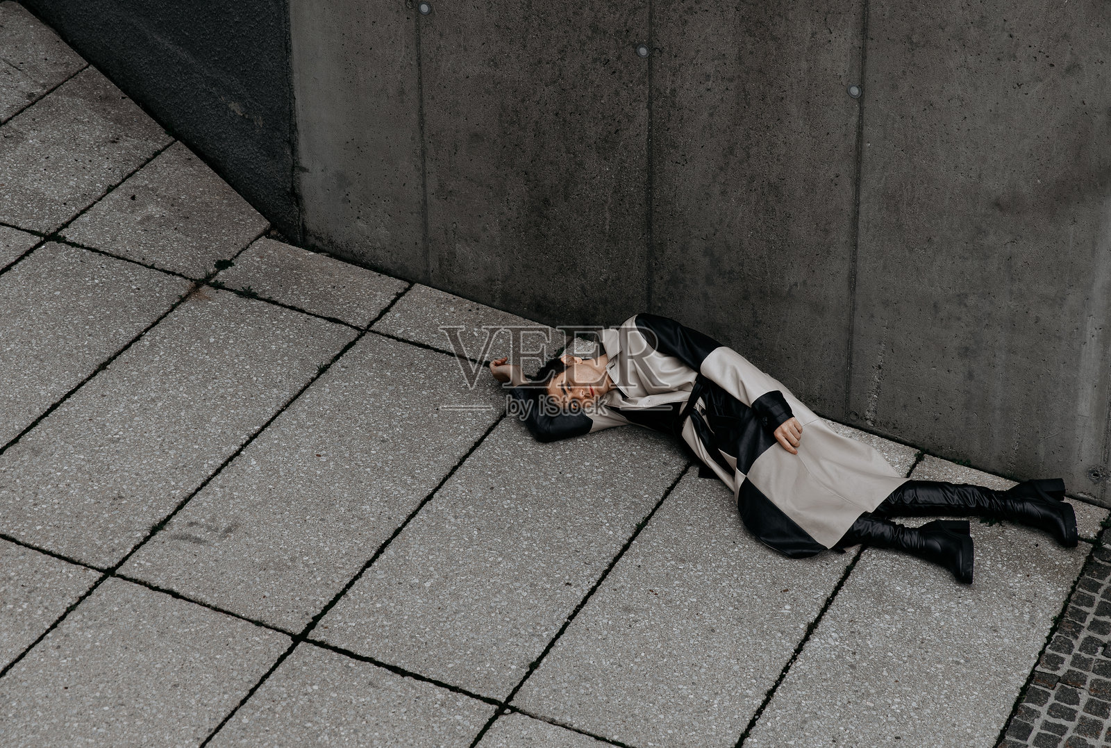 身着时尚服装的高加索女性，躺在户外的城市人行道上照片摄影图片