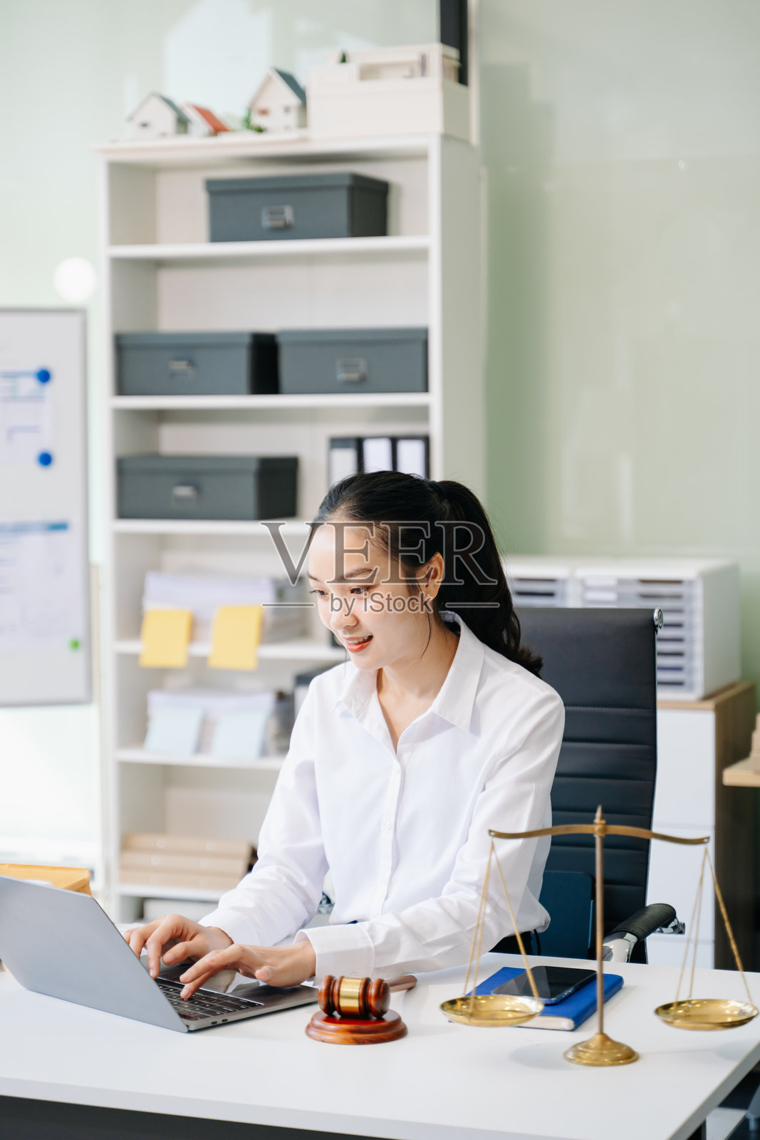 一位女律师在办公桌前，伴有法槌和天平，庆祝成功，桌上放着文件照片摄影图片