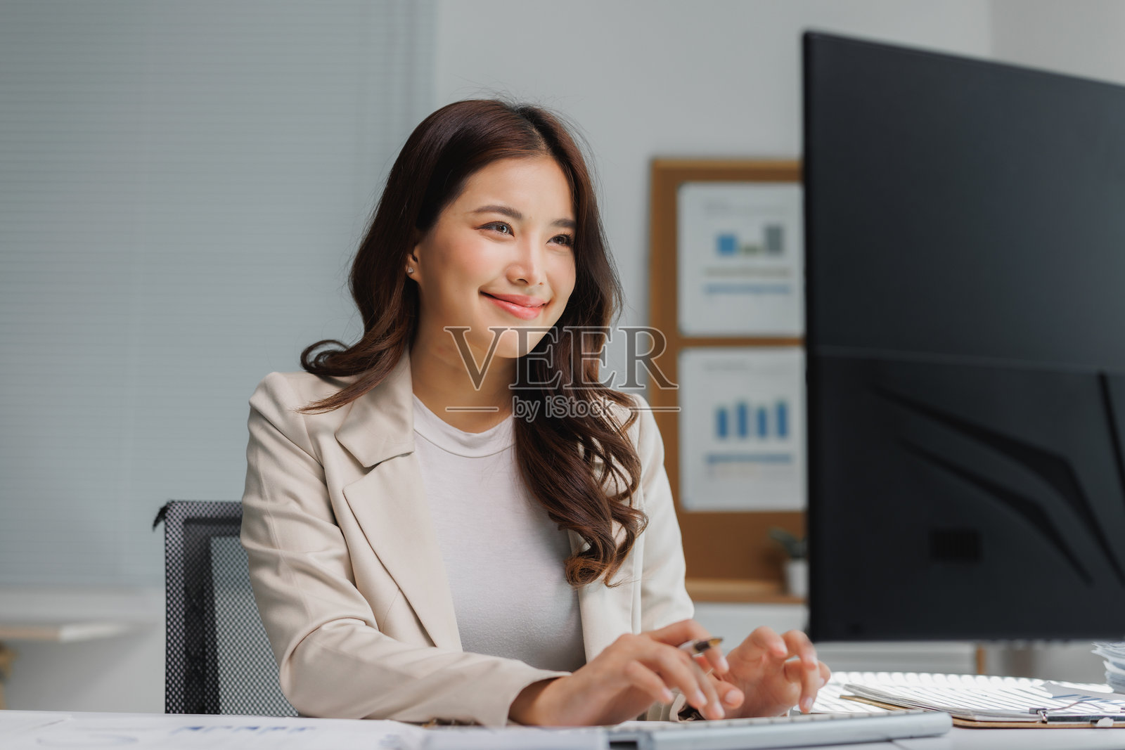 年轻的亚洲女性在电脑前快乐地工作微笑照片摄影图片