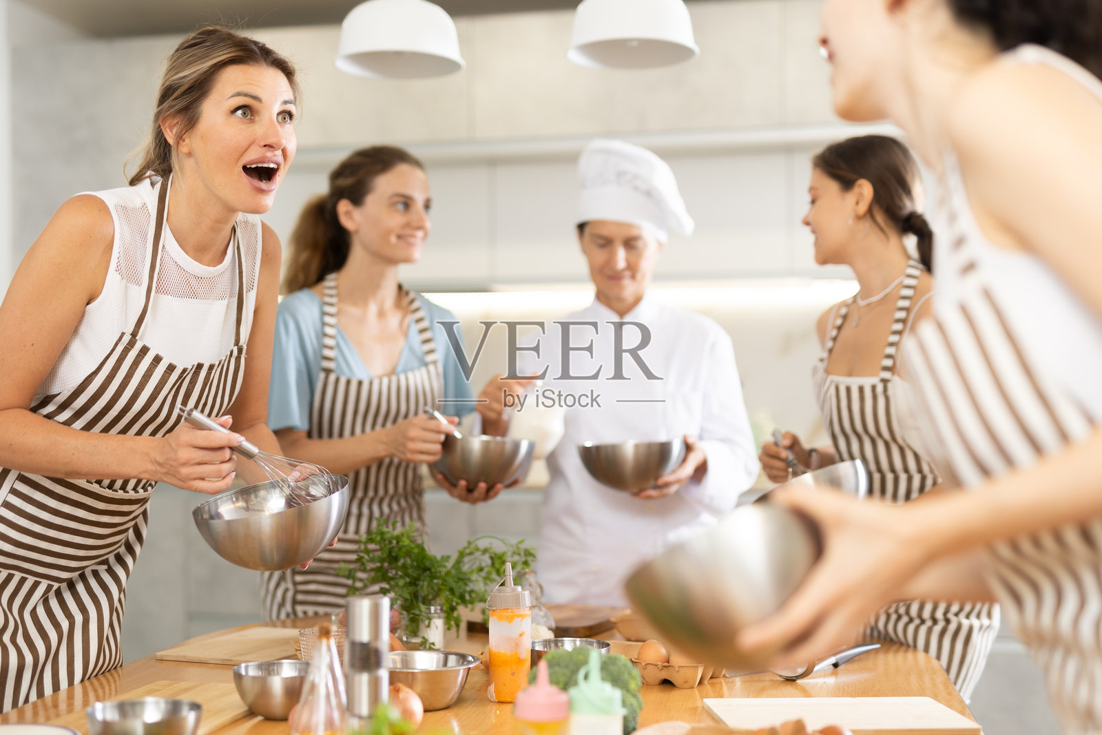 年轻女子拿着碗，与其他成员交谈照片摄影图片