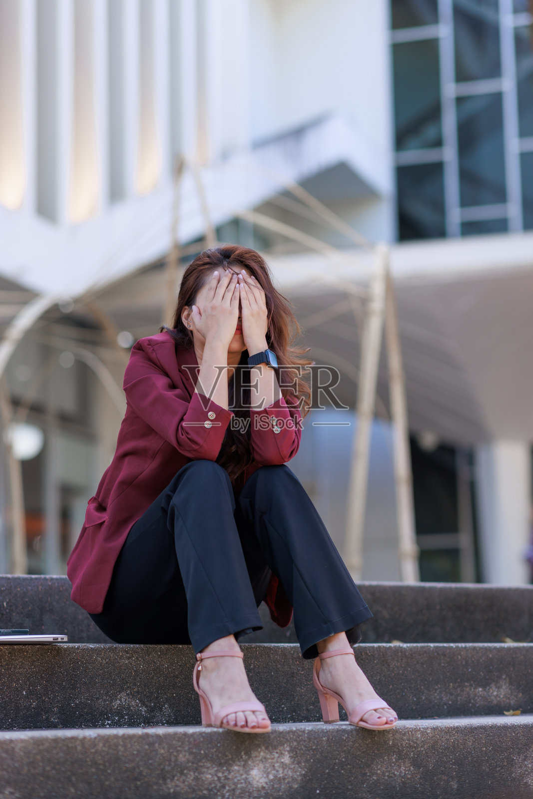 一名女子坐在楼梯上，用手捂着脸，感到压力重重照片摄影图片